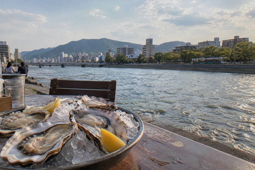 A plate of freshly shucked raw Hiroshima oysters on ice with lemon