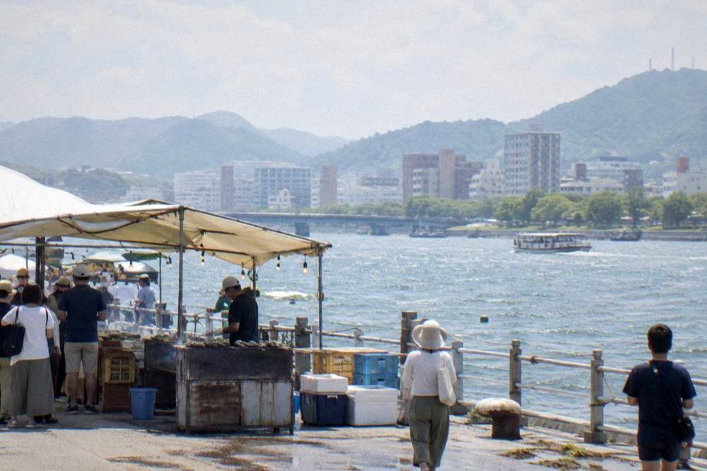 Festival stalls serving grilled oysters to visitors along a waterfront in Hiroshima