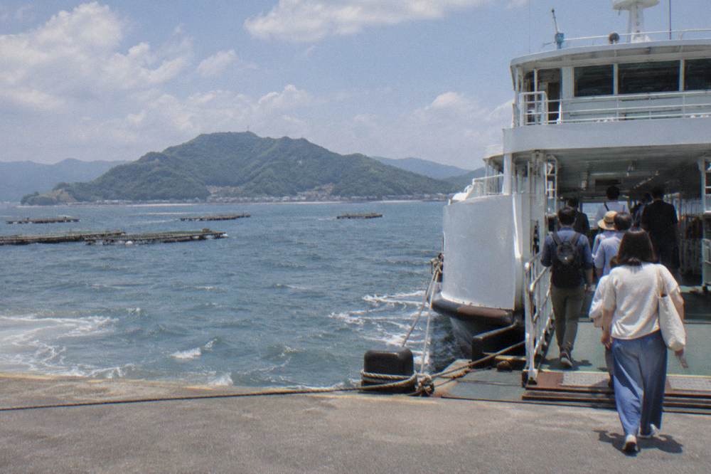 A sleek high-speed ferry moored at a city pier with modern buildings behind it