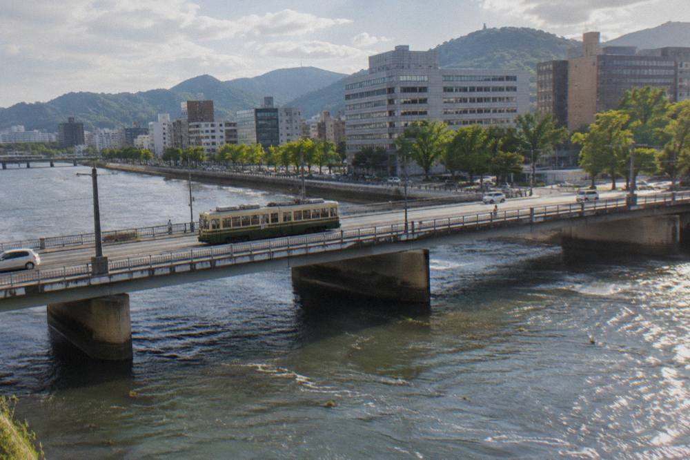 Hiroden streetcar crossing a bridge in central Hiroshima with office buildings behind
