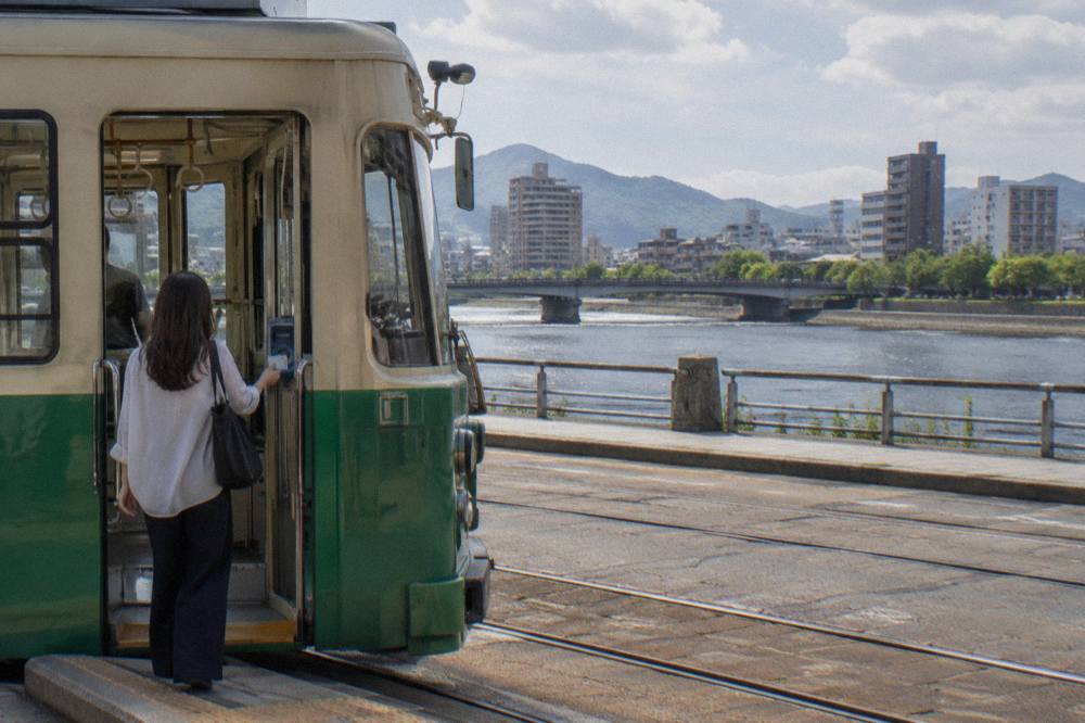 A passenger tapping a transit card at a streetcar door in Hiroshima