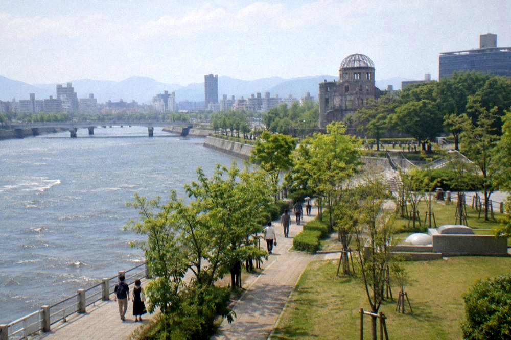 Visitors walking quietly along a tree-lined path in the Hiroshima Peace Memorial Park