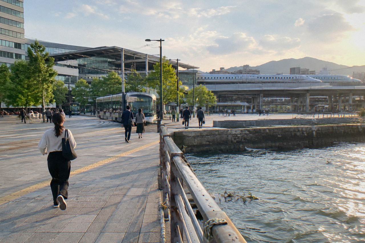 A sleek bullet train waiting at a platform beside modern station buildings