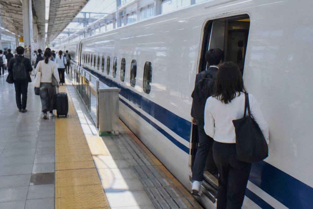 Passengers boarding a white bullet train at an indoor station platform