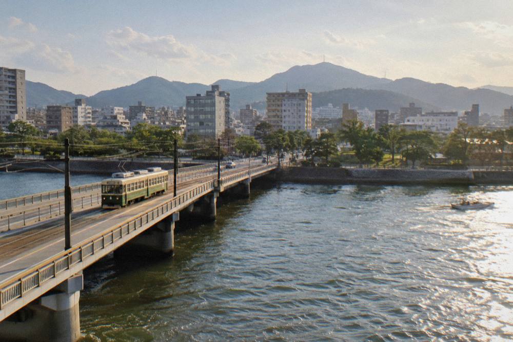 A streetcar crossing a bridge over a Hiroshima river toward the city centre