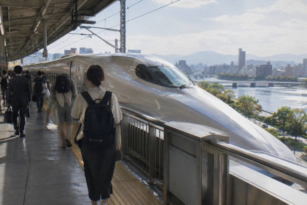 Passengers walking along a Shinkansen platform with a bullet train nose visible