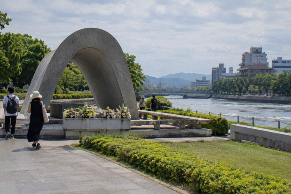 Visitors walk slowly past a cenotaph memorial in the green riverside Peace Memorial Park.