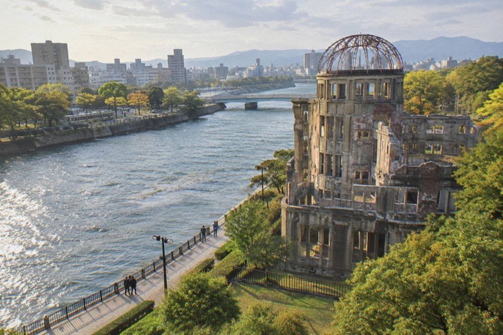 The skeletal iron frame of the Atomic Bomb Dome stands quiet above the river bank.