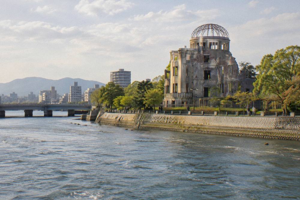 The Atomic Bomb Dome seen across the river, its skeletal frame against a pale sky.