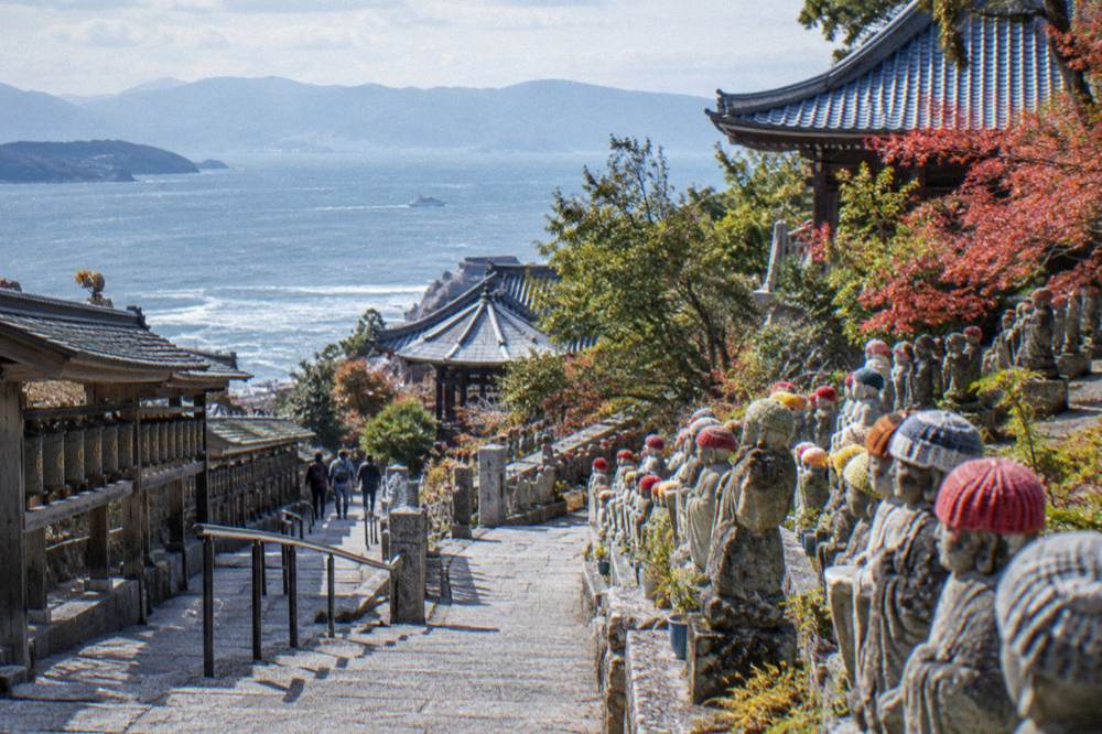 Rows of small stone statues in caps lining a path at Daisho-in Temple on Miyajima.