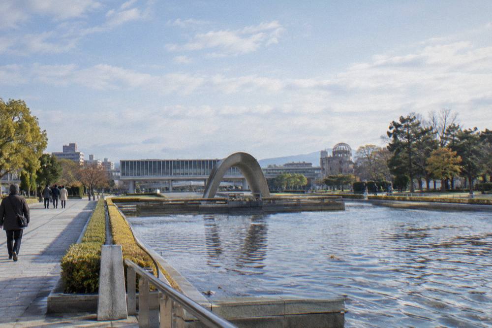 The reflecting pool and cenotaph in Hiroshima Peace Memorial Park with the museum building beyond
