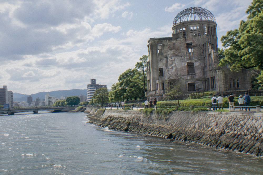 Visitors standing at the fence around the Atomic Bomb Dome in daylight