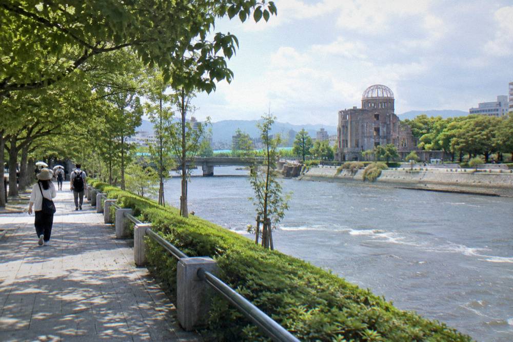 Visitors walking quietly along a tree-lined path in the Hiroshima Peace Memorial Park
