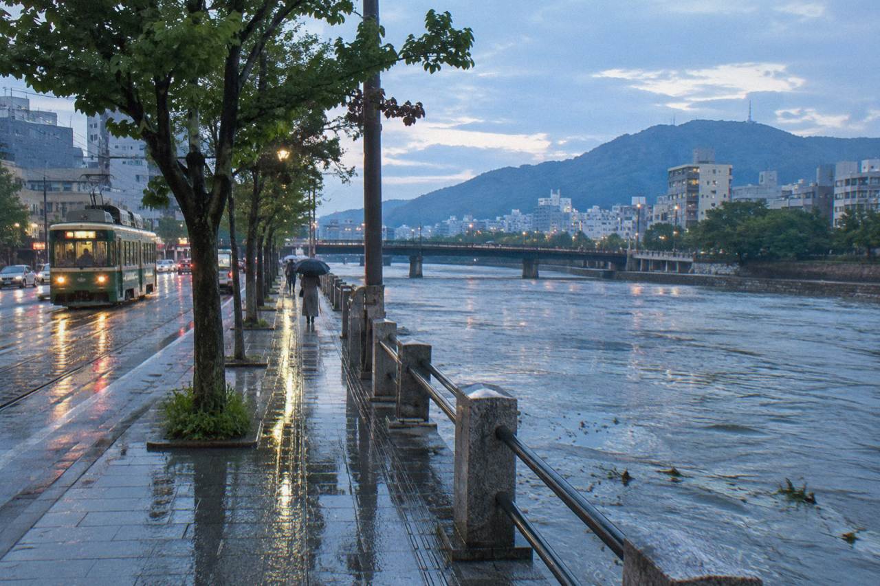 A rainy street in central Hiroshima with wet pavement reflecting shop lights