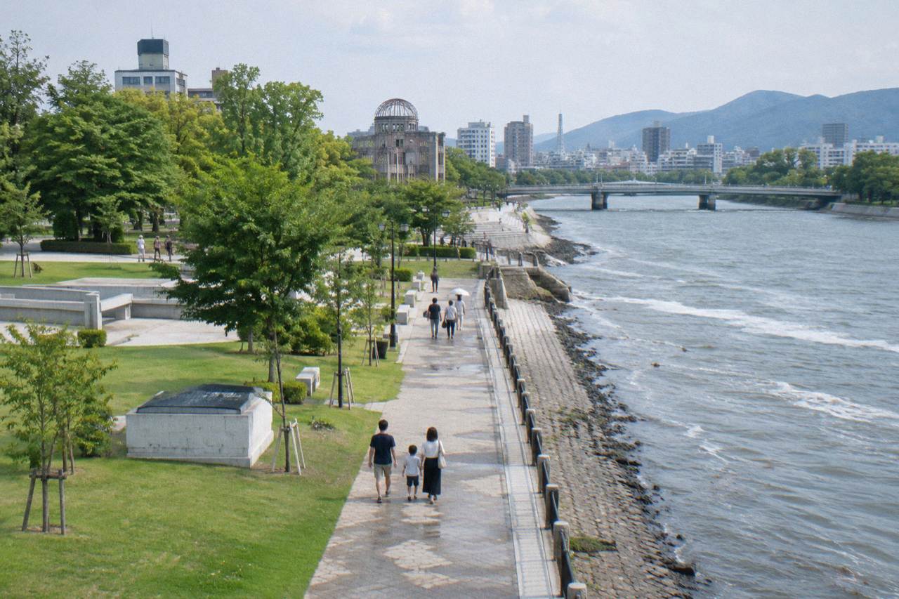Families walking along a riverside path in Hiroshima near the Peace Memorial Park