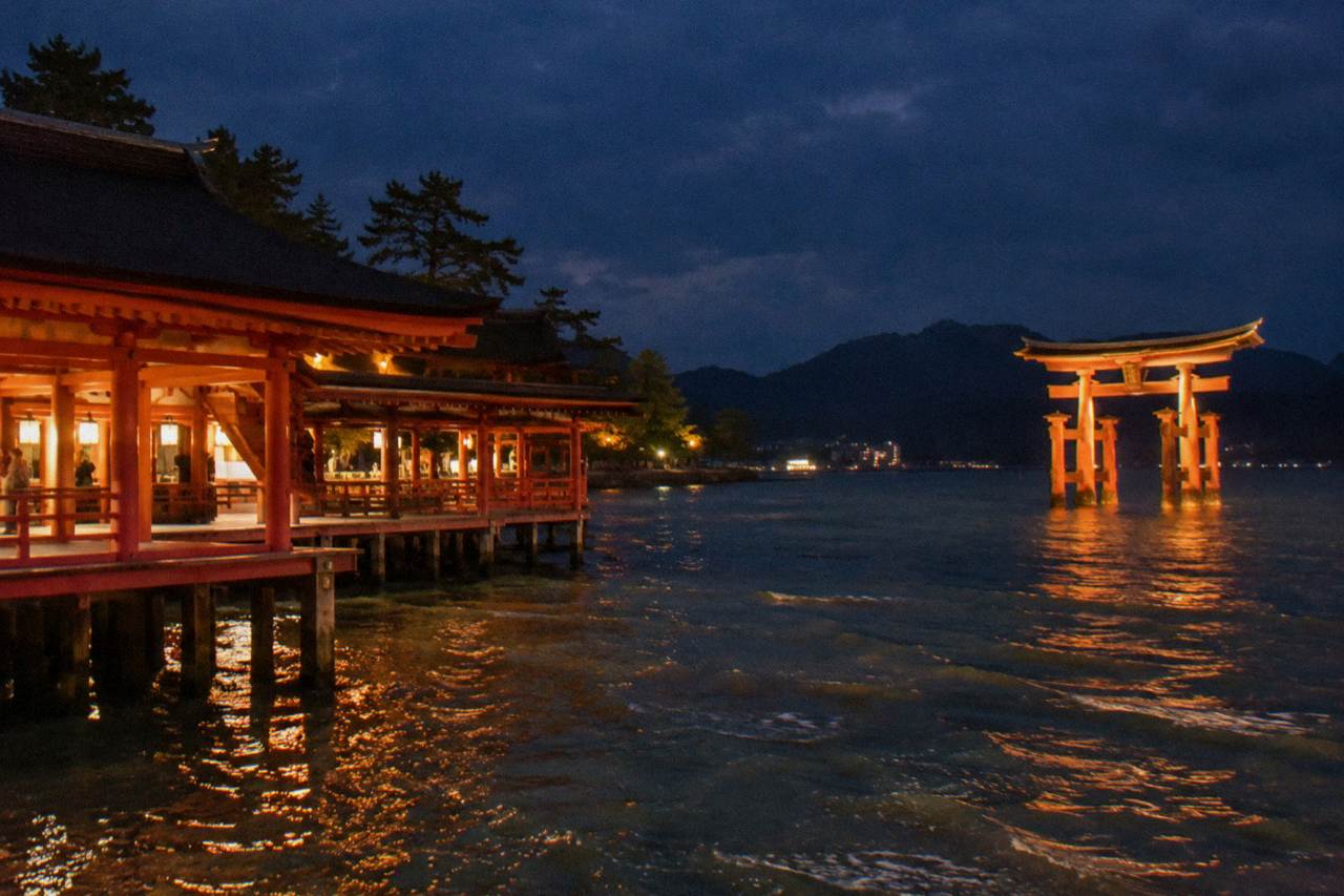 The illuminated Great Torii gate of Miyajima standing in dark water at night