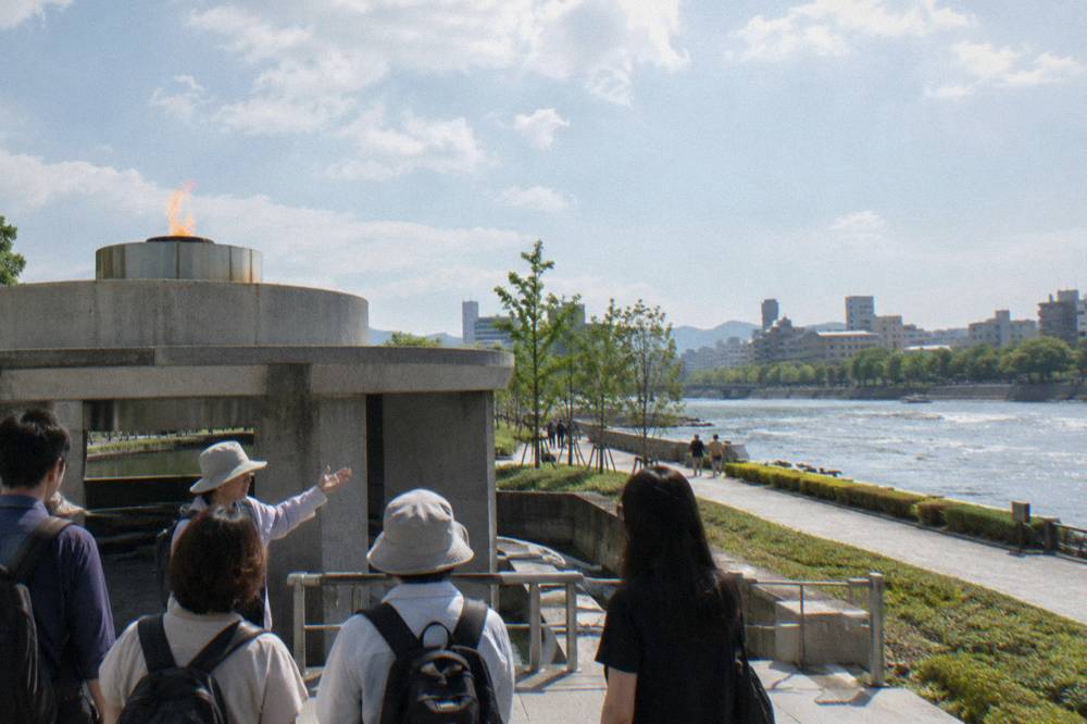 A guide speaking with a small group beside the Peace Flame in Hiroshima